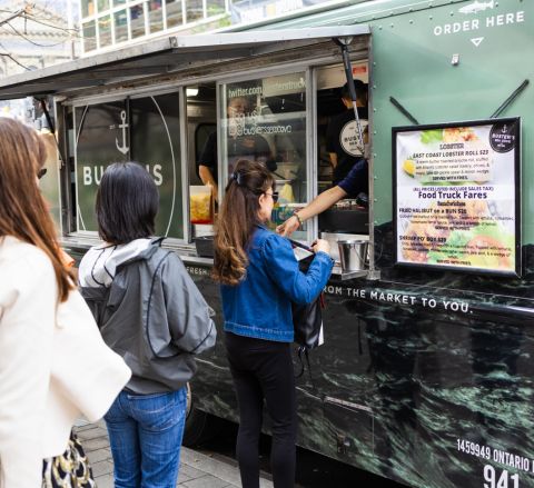 Three people line up to order from a food truck outside