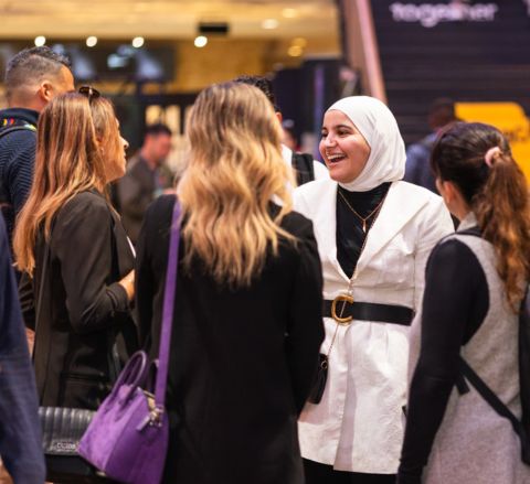 A person smiles as they talk to two others at a past networking event